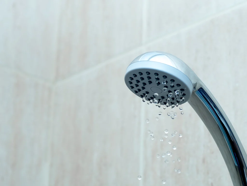 Showerhead with weak water flow, showing a common sign you may need a plumber for low water pressure