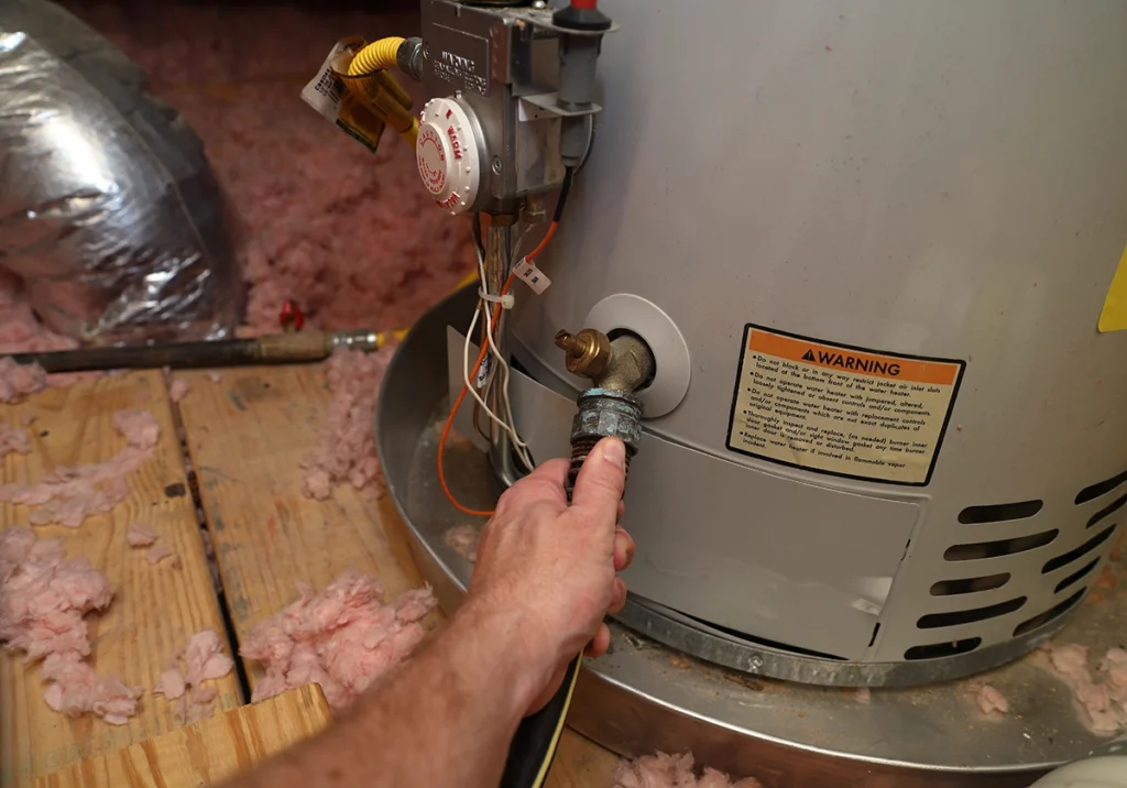 Technician working on a residential water heater during same day water heater replacement in Boston, showing factors that can affect cost.