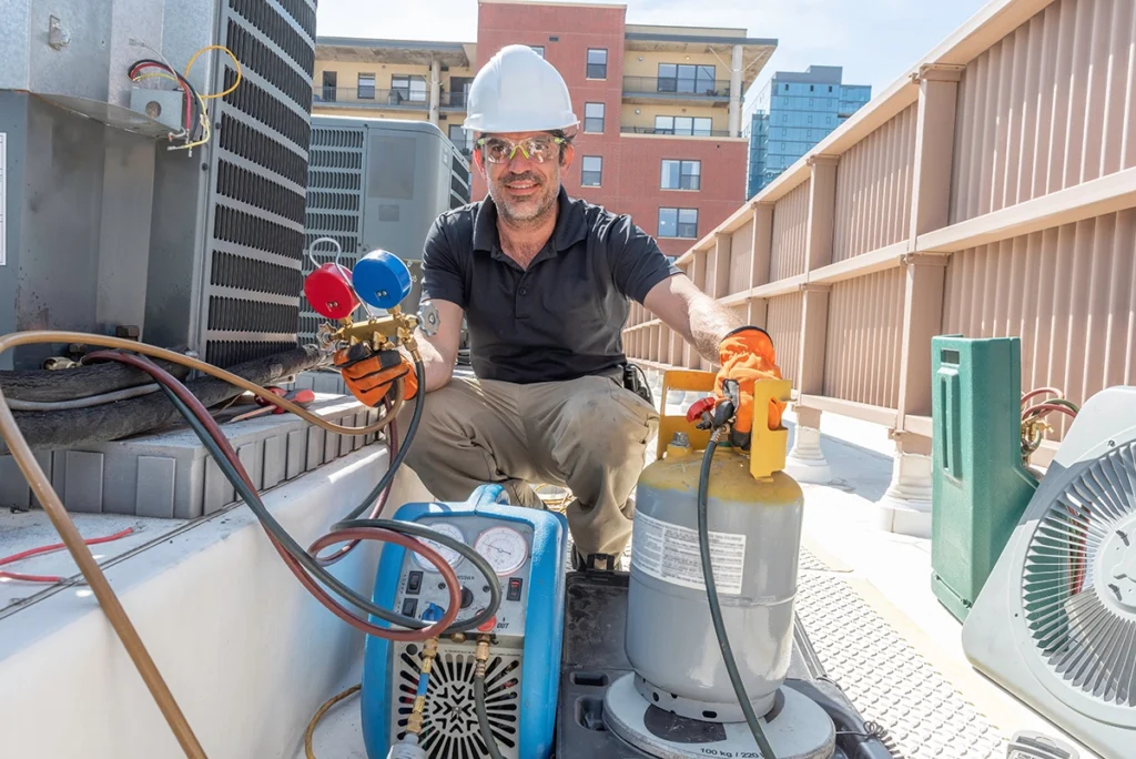 HVAC technician performing commercial HVAC maintenance on rooftop air conditioning equipment.